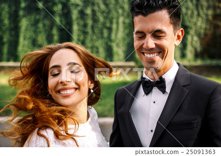 Groom laughs and closes his eyes while bride Groom laughs and closes his eyes while bride 25091363