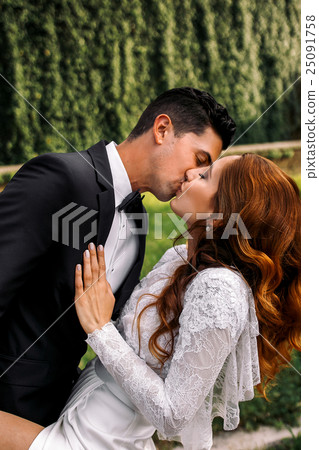 Groom bends bride over, holds her leg and kisses Groom bends bride over, holds her leg and kisses 25091758