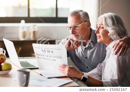 Stock Photo: Happy and caring old couple reading newspaper at