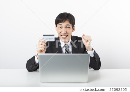 A businessman with a card in front of a personal computer 25092305