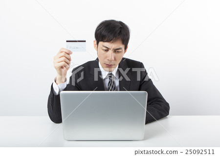 與一張卡片的一個商人在個人計算機前面 25092511