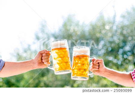 Hands of two men holding mugs of of beer 25093099