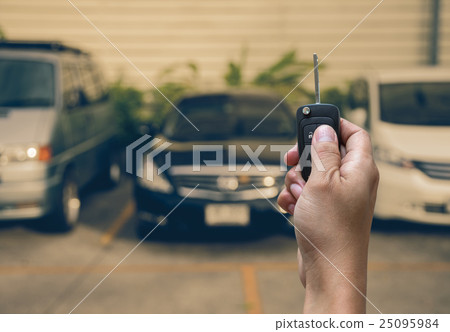 Hand holding and touching the keys over photo blurred of used car for open the door car, transportation and ownership concept 25095984