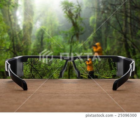 Conceptual image of rain forest focused in glasses lenses over the photo blurred of Traveller taking photo at Beautiful rain forest 25096300