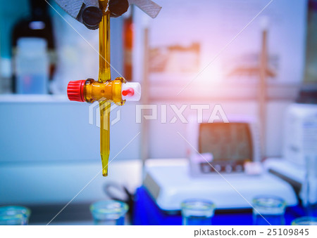 Burette filled with yellow liquid in laboratory. Burette filled with yellow liquid in laboratory. 25109845