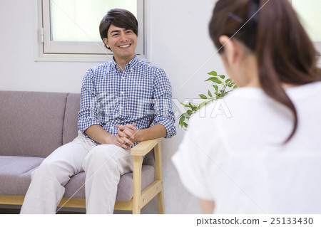 A man sitting on a sofa and a woman sitting on a bed A man sitting on a sofa and a woman sitting on a bed 25133430
