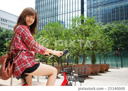 A young Japanese woman riding a bicycle with a smile 25140000