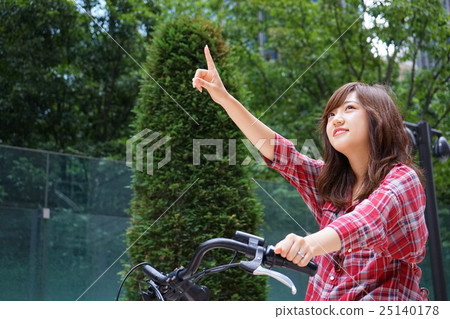 A young Japanese woman who rides a bicycle and touches her finger 25140178