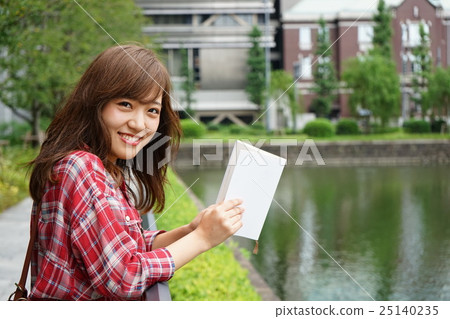 一位年輕的日本女士在外面讀書 25140235