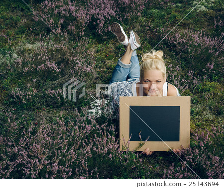 Young woman lying on the grass and holding a slate Young woman lying on the grass and holding a slate 25143694