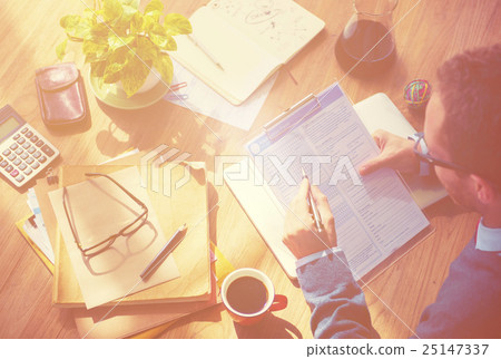 Hipster Man Casually Filing In The Application Form On His Wooden Desk Hipster Man Casually Filing In The Application Form On His Wooden Desk 25147337