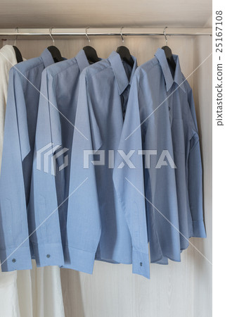 row of blue color shirts hanging on rail 25167108