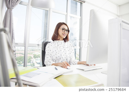 Smiling asian businesswoman working at office desk 25179684
