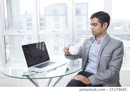Businessman using laptop holding coffee cup Businessman using laptop holding coffee cup 25179685