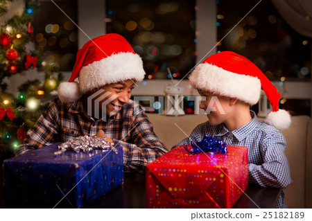 Two kids near Christmas presents. Two kids near Christmas presents. 25182189