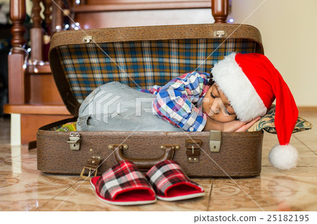 Black boy sleeps in suitcase. 25182195