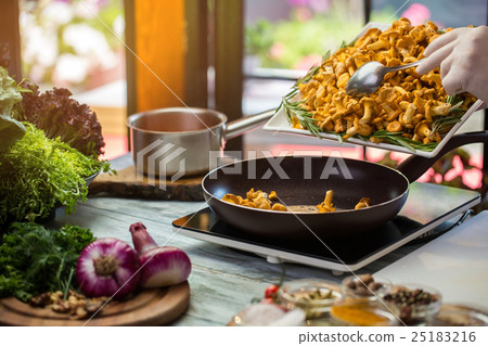 Yellow mushrooms on black pan. 25183216