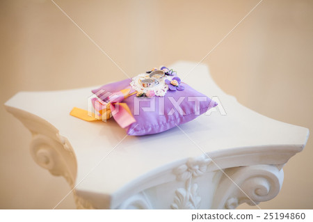 Golden wedding rings on decorated little purple Golden wedding rings on decorated little purple 25194860