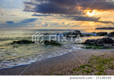 图库照片 morning sun rays illuminate sandy beach with rocks