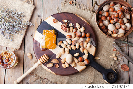 Assortment of nuts and honey Wooden cutting board 25197385