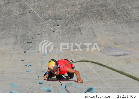 Girl climbing on artificial climbing wall of a dam Girl climbing on artificial climbing wall of a dam 25211409