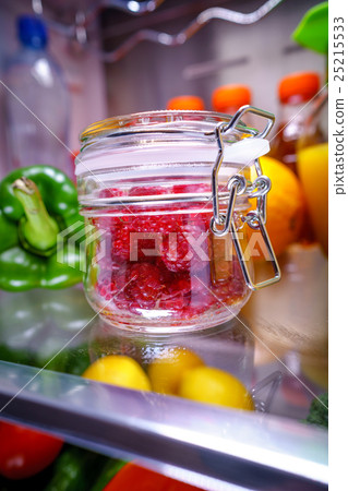 Fresh raspberries in a glass jar on a shelf open refrigerator 25215533