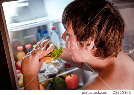 Hungry man holding a sandwich in his hands and standing next to 25215566
