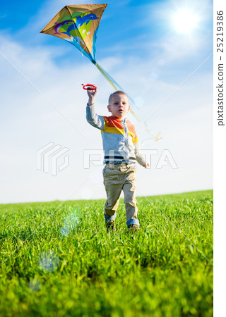 Young boy playing with his kite in a green field. Young boy playing with his kite in a green field. 25219386