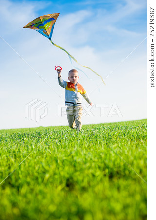 Young boy playing with his kite in a green field. Young boy playing with his kite in a green field. 25219387