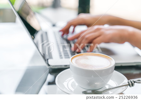 Closeup of Latte Coffee art and woman hand typing on laptop keyboard . 25226936