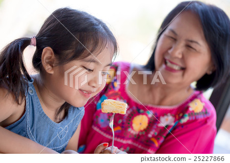 Asian senior woman feeding honey toast for child 25227866