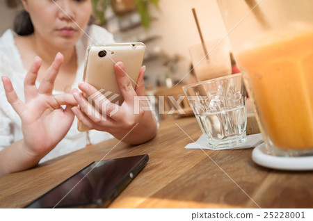 Woman using phone in cafe 25228001