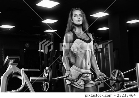 Brutal athletic woman pumping up muscles with dumbbells 25235464