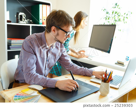 Young artist drawing something on graphic tablet at the office Young artist drawing something on graphic tablet at the office 25239303