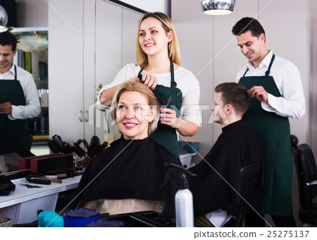 Blonde cuts hair at salon 25275137