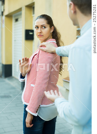 brunette girl asking man to stop bothering her outdoors 25275281