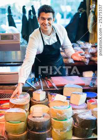 Smiling male seller offering assortment of cheese 25275337