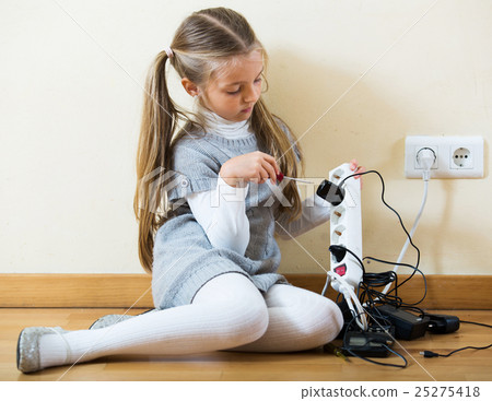 Little girl with socket extender and charging units indoors 25275418