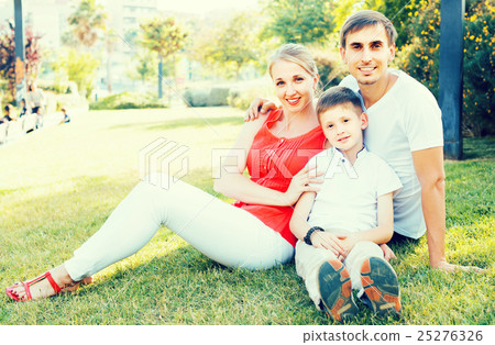 parent with boy in teen age sitting on green grass in park parent with boy in teen age sitting on green grass in park 25276326