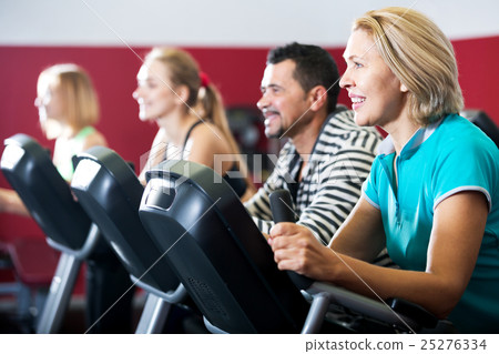 People training on exercise bikes together People training on exercise bikes together 25276334