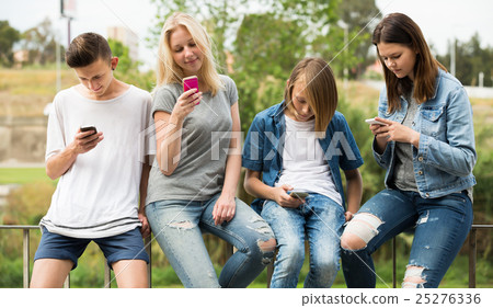 Teenagers friends playing with mobile phones Teenagers friends playing with mobile phones 25276336