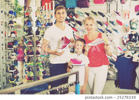 Cheerful young parents with boy in school age shopping shoes Cheerful young parents with boy in school age shopping shoes 25276339
