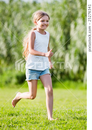 Glad girl in elementary school age running on grass Glad girl in elementary school age running on grass 25276341