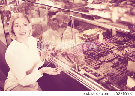 Happy blonde pensioner buying chocolate Happy blonde pensioner buying chocolate 25276558