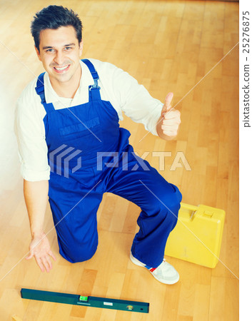 Happy handyman placing floor during renewal Happy handyman placing floor during renewal 25276875