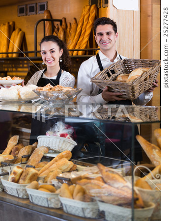 Friendly man and woman selling pastry and loaves Friendly man and woman selling pastry and loaves 25277428