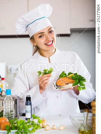 Happy young cook with prepared trout in plate Happy young cook with prepared trout in plate 25277904