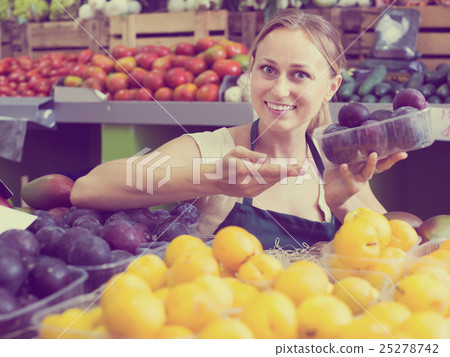 Portrait of smiling woman selling ripe fresh plums 25278742
