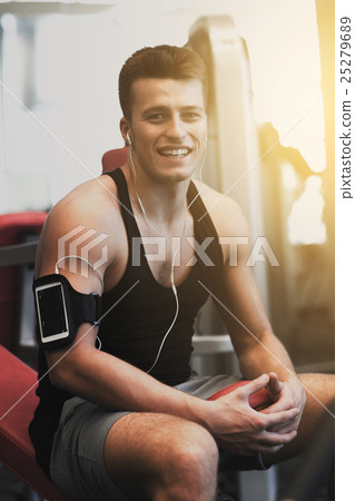 smiling sportsman with smartphone and earphones smiling sportsman with smartphone and earphones 25279689