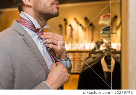close up of man tying tie at clothing store mirror close up of man tying tie at clothing store mirror 25279748